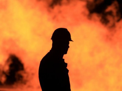 An unidentified oil worker walks in front of a natural gas flame burning off in the Persian Gulf desert oil field of Sakhir, Bahrain (Image: AP/H. Jamali)